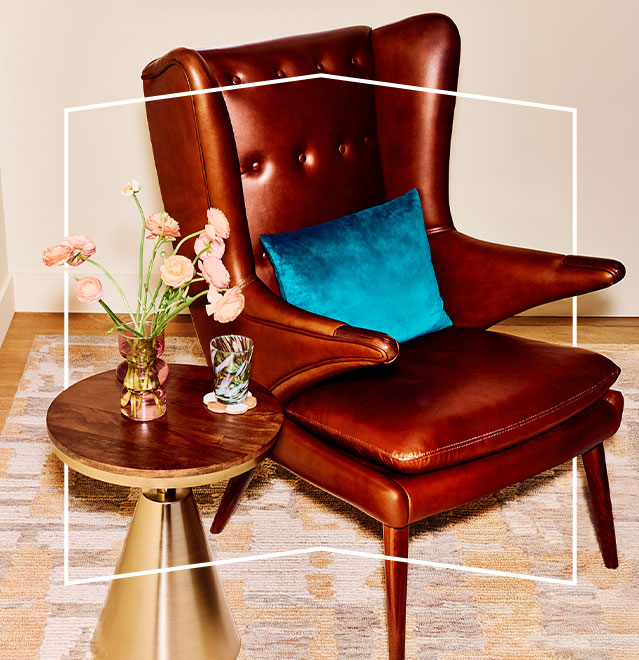 A living room featuring a leather wingback chair & a stylish wooden coffee table.