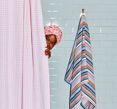 A pink gingham shower curtain and a striped towel.