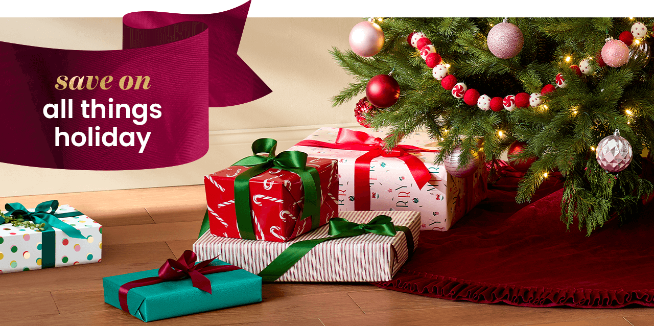 Gifts wrapped in patterned wrapping paper, tied with velvet bows, under artificial Christmas tree